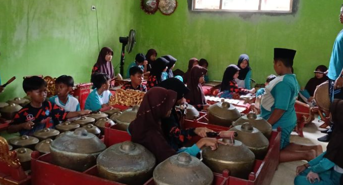 Karawitan, sebagai salah satu bentuk seni musik tradisional Jawa, memegang peranan penting dalam budaya masyarakat Indonesia. Di Purworejo, sebuah kabupaten yang terletak di provinsi Jawa Tengah, karawitan bukan hanya sekadar hiburan, tetapi juga merupakan bagian integral dari identitas budaya masyarakat setempat. Karawitan memiliki berbagai elemen, mulai dari alat musik seperti gamelan hingga vokal yang khas, yang menjadikannya unik dan menarik. Namun, seiring dengan perkembangan zaman dan modernisasi, pelestarian karawitan menghadapi tantangan yang cukup besar. Oleh karena itu, perlu adanya upaya untuk melestarikan karawitan di Purworejo agar tidak punah. Artikel ini akan membahas beberapa upaya pelestarian karawitan di Purworejo melalui empat sub judul yang berbeda. 1. Pendidikan dan Pelatihan Karawitan Pendidikan dan pelatihan merupakan langkah awal yang sangat penting dalam pelestarian karawitan. Di Purworejo, berbagai lembaga pendidikan, baik formal maupun non-formal, telah berupaya untuk mengajarkan seni karawitan kepada generasi muda. Sekolah-sekolah seni dan komunitas musik lokal sering kali mengadakan kelas dan workshop tentang karawitan, di mana anak-anak dan remaja diajarkan cara memainkan alat musik gamelan dan menyanyi dengan teknik vokal yang benar. Melalui pendidikan ini, anak-anak tidak hanya belajar tentang musik, tetapi juga memahami sejarah dan filosofi yang terkandung dalam setiap nada dan irama. Selain itu, pelatihan karawitan juga menjadi sarana untuk menciptakan rasa cinta dan bangga terhadap budaya lokal. Dengan mempelajari karawitan, generasi muda diharapkan dapat menghargai warisan budaya nenek moyang mereka. Kegiatan ini juga memberikan kesempatan bagi mereka untuk berinteraksi dengan para maestro karawitan yang memiliki pengalaman dalam bidang ini. Pertukaran pengetahuan dan pengalaman antara generasi tua dan muda sangat penting untuk memastikan bahwa teknik dan tradisi karawitan dapat diwariskan dengan baik. Program-program pelatihan yang terstruktur juga dapat membantu menciptakan kelompok-kelompok karawitan di sekolah-sekolah dan komunitas lokal. Kelompok-kelompok ini dapat menjadi wadah bagi para peserta untuk berlatih dan menampilkan karya mereka di berbagai acara, baik di tingkat lokal maupun nasional. Dengan memberikan kesempatan untuk tampil, para peserta akan lebih termotivasi untuk belajar dan melestarikan karawitan. Namun, tantangan yang dihadapi dalam pendidikan dan pelatihan ini adalah kurangnya minat dari generasi muda yang lebih terpapar pada budaya pop dan teknologi modern. Oleh karena itu, perlu adanya inovasi dalam penyampaian materi dan pendekatan yang lebih menarik agar anak-anak dan remaja mau terlibat aktif dalam pelestarian karawitan. Dengan cara ini, diharapkan minat masyarakat akan karawitan semakin meningkat. 2. Festival dan Even Budaya Festival dan event budaya menjadi salah satu upaya efektif dalam pelestarian karawitan di Purworejo. Kegiatan ini tidak hanya menjadi ajang unjuk kebolehan para seniman karawitan, tetapi juga menjadi sarana untuk memperkenalkan dan mempromosikan seni karawitan kepada masyarakat luas. Festival yang diselenggarakan secara rutin, seperti Festival Karawitan Purworejo, mampu menarik perhatian banyak orang dan meningkatkan kesadaran akan pentingnya menjaga warisan budaya ini. Dalam festival tersebut, berbagai pertunjukan karawitan ditampilkan, mulai dari gamelan tradisional, tari-tarian, hingga vokal solo yang mengusung tema-tema lokal. Hal ini memberikan ruang bagi para seniman untuk mengekspresikan kreativitas mereka dan mengenalkan berbagai bentuk karawitan yang ada di Purworejo. Selain itu, festival juga seringkali diisi dengan seminar, lokakarya, dan diskusi mengenai pentingnya pelestarian karawitan, yang melibatkan para ahli dan seniman dari berbagai daerah. Partisipasi masyarakat dalam festival ini sangat penting. Dengan melibatkan masyarakat, baik sebagai penampil maupun penonton, festival dapat meningkatkan rasa memiliki terhadap budaya karawitan. Masyarakat diharapkan dapat merasakan pengalaman langsung dan terhubung dengan akar budaya mereka melalui pertunjukan yang disajikan. Selain itu, festival juga dapat menjadi ajang bagi generasi muda untuk bertemu dan belajar dari para seniman senior, sehingga proses transfer pengetahuan dapat berjalan dengan baik. Namun, untuk menyelenggarakan festival yang sukses, dibutuhkan dukungan dari berbagai pihak, termasuk pemerintah, komunitas, dan sponsor. Oleh karena itu, kerjasama lintas sektor sangat diperlukan agar pelaksanaan festival dapat berjalan lancar dan memberikan dampak yang signifikan terhadap pelestarian karawitan. Selain itu, festival yang diadakan secara berkala dapat membantu mengukuhkan identitas budaya Purworejo sebagai daerah yang kaya akan seni karawitan. 3. Dukungan Pemerintah dan Kebijakan Publik Dukungan pemerintah sangat krusial dalam upaya pelestarian karawitan di Purworejo. Kebijakan publik yang pro terhadap seni dan budaya dapat memberikan ruang yang lebih besar bagi pengembangan karawitan. Pemerintah daerah melalui dinas terkait seharusnya menginisiasi program-program yang mendukung pelestarian karawitan, baik dalam hal pendanaan, pemfasilitasan, maupun promosi. Program-program tersebut bisa berupa bantuan untuk kelompok karawitan, penyediaan alat musik, pelatihan bagi guru seni, serta dukungan untuk penyelenggaraan festival seni. Selain itu, pemerintah juga memiliki peran penting dalam menyusun regulasi yang mendukung pelestarian budaya. Misalnya, dengan mengeluarkan peraturan yang mengharuskan pendidikan seni tradisional, termasuk karawitan, diajarkan di sekolah-sekolah. Kebijakan ini diharapkan dapat memastikan bahwa generasi muda memiliki kesempatan untuk belajar dan memahami seni karawitan sebagai bagian dari kurikulum pendidikan. Dengan demikian, karawitan tidak hanya dipandang sebagai seni, tetapi juga sebagai pelajaran yang penting dalam pembentukan karakter dan identitas. Inisiatif pemerintah dalam mendukung pelestarian karawitan juga dapat berupa kerjasama dengan komunitas dan lembaga swasta. Misalnya, program kolaborasi antara pemerintah dengan komunitas seni lokal dapat menghasilkan kegiatan yang lebih beragam dan menarik. Dengan melibatkan berbagai pihak, upaya pelestarian karawitan akan menjadi lebih efektif dan menyeluruh. Kegiatan-kegiatan tersebut juga dapat meningkatkan kesadaran masyarakat tentang pentingnya menjaga warisan budaya. Namun, tantangan yang dihadapi dalam dukungan pemerintah ini adalah keterbatasan anggaran dan sumber daya manusia yang memiliki pemahaman mendalam tentang seni karawitan. Oleh karena itu, perlu adanya pelatihan untuk para pegawai pemerintah agar mereka lebih memahami dan mengapresiasi seni karawitan serta pentingnya perannya dalam pembangunan budaya di daerah. Dengan demikian, pelestarian karawitan di Purworejo akan mendapat dukungan yang lebih kuat dan berkelanjutan. 4. Peran Komunitas dan Masyarakat Komunitas dan masyarakat memegang peranan penting dalam pelestarian karawitan di Purworejo. Kegiatan-kegiatan yang dilakukan oleh komunitas seni lokal sangat berpengaruh dalam menjaga keberlangsungan karawitan. Berbagai kelompok karawitan yang ada di masyarakat, baik yang berbasis di desa maupun kota, seringkali menggelar pertunjukan rutin, latihan bersama, dan kegiatan lainnya yang bertujuan untuk melestarikan budaya ini. Keterlibatan masyarakat dalam kegiatan ini akan menciptakan rasa memiliki dan tanggung jawab terhadap warisan budaya mereka. Selain itu, peran komunitas juga sangat penting dalam menciptakan jaringan dan kolaborasi. Kelompok-kelompok karawitan dapat saling bertukar pengalaman, pengetahuan, dan sumber daya untuk meningkatkan kualitas pertunjukan mereka. Melalui kolaborasi ini, mereka bisa menciptakan inovasi dalam penyajian karawitan yang menarik dan relevan dengan konteks zaman sekarang. Misalnya, menggabungkan elemen-elemen modern dengan tradisional dalam pertunjukan karawitan, sehingga dapat menarik perhatian generasi muda. Sosialisasi dan promosi karawitan di tingkat lokal juga menjadi tanggung jawab masyarakat. Melalui kegiatan-kegiatan seperti pentas seni, bazar budaya, dan lokakarya, masyarakat bisa mengenalkan seni karawitan kepada khalayak yang lebih luas. Dengan cara ini, masyarakat diharapkan dapat menarik minat generasi muda untuk terlibat dalam pelestarian karawitan. Kesadaran kolektif untuk menjaga dan mengembangkan karawitan dapat menjadi kekuatan yang besar dalam melestarikan budaya ini. Namun, tantangan yang dihadapi adalah minimnya sumber daya dan fasilitas yang memadai untuk mendukung kegiatan komunitas. Oleh karena itu, diperlukan kerjasama dengan pihak-pihak lain, seperti pemerintah dan lembaga swasta, untuk mendapatkan dukungan yang lebih baik. Dengan adanya dukungan tersebut, diharapkan kegiatan komunitas dalam pelestarian karawitan dapat lebih berkembang dan memberikan dampak yang lebih luas bagi masyarakat. Kesimpulan Pelestarian karawitan di Purworejo merupakan upaya yang memerlukan kerjasama dari berbagai pihak, termasuk pemerintah, masyarakat, dan komunitas seni. Melalui pendidikan dan pelatihan yang tepat, festival budaya yang menarik, dukungan kebijakan dari pemerintah, serta peran aktif masyarakat, karawitan di Purworejo dapat dilestarikan dan diperkenalkan kepada generasi mendatang. Meskipun tantangan yang dihadapi cukup besar, dengan keberpihakan dan dukungan yang solid, karawitan dapat terus hidup dan menjadi bagian dari identitas budaya masyarakat Purworejo. Dengan demikian, warisan budaya yang kaya ini tidak hanya dapat dinikmati oleh generasi sekarang, tetapi juga dapat diwariskan kepada generasi yang akan datang.